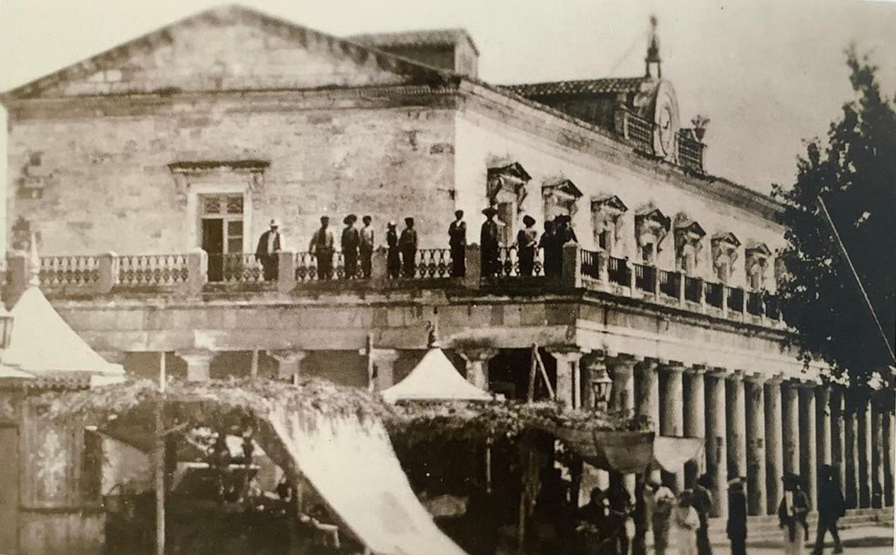 Εικ. 6, Άποψη της εικ. 5. Διακρίνονται εμπορεύματα στο ισόγειο  και κόσμος στον εξώστη.